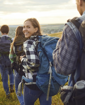 Healthy U Integrated - Group of teenagers and young adults hiking with one teenage girl looking back and smiling